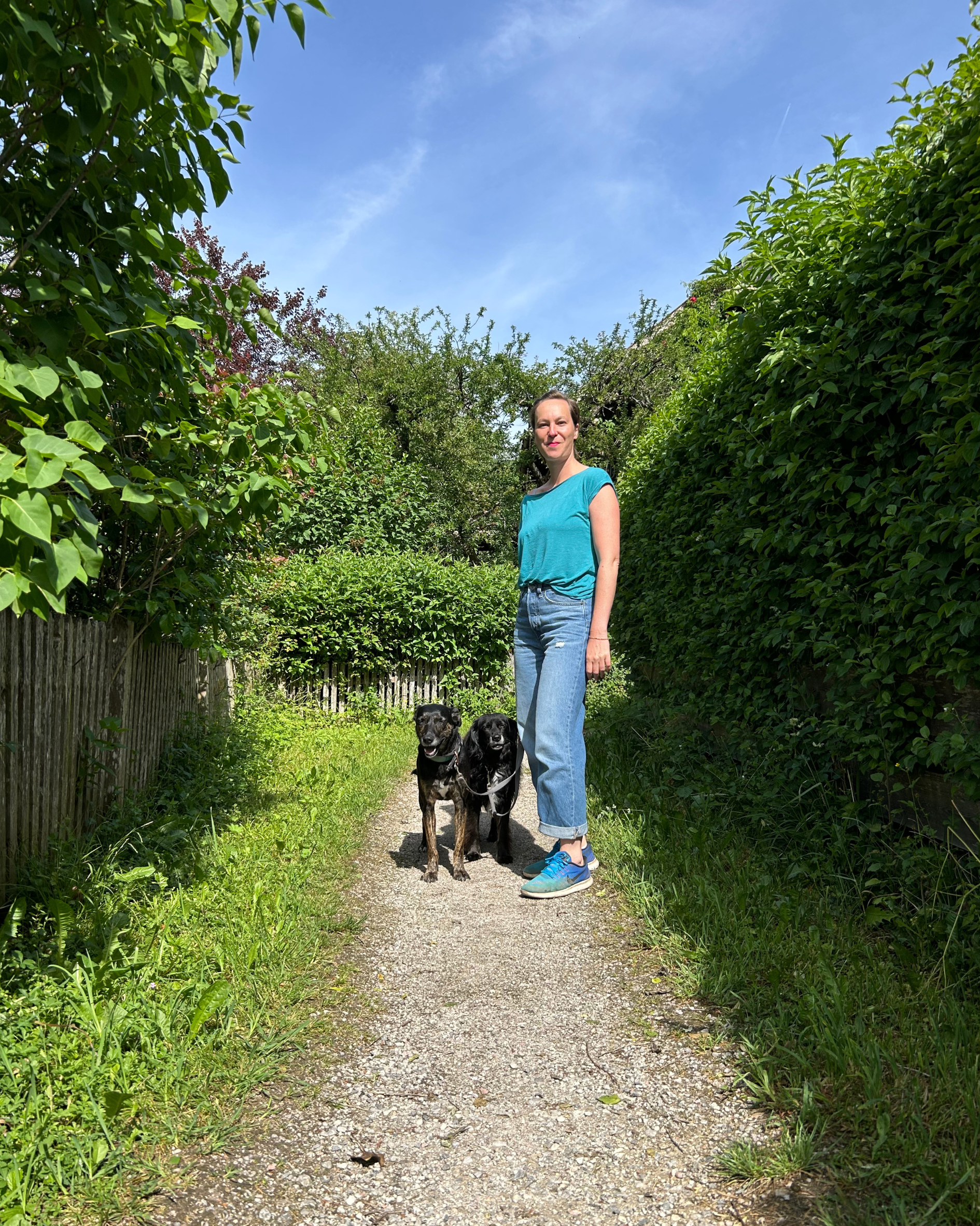 Philine Passin steht lächelnd mit ihren Hunden auf einem Weg im Grünen