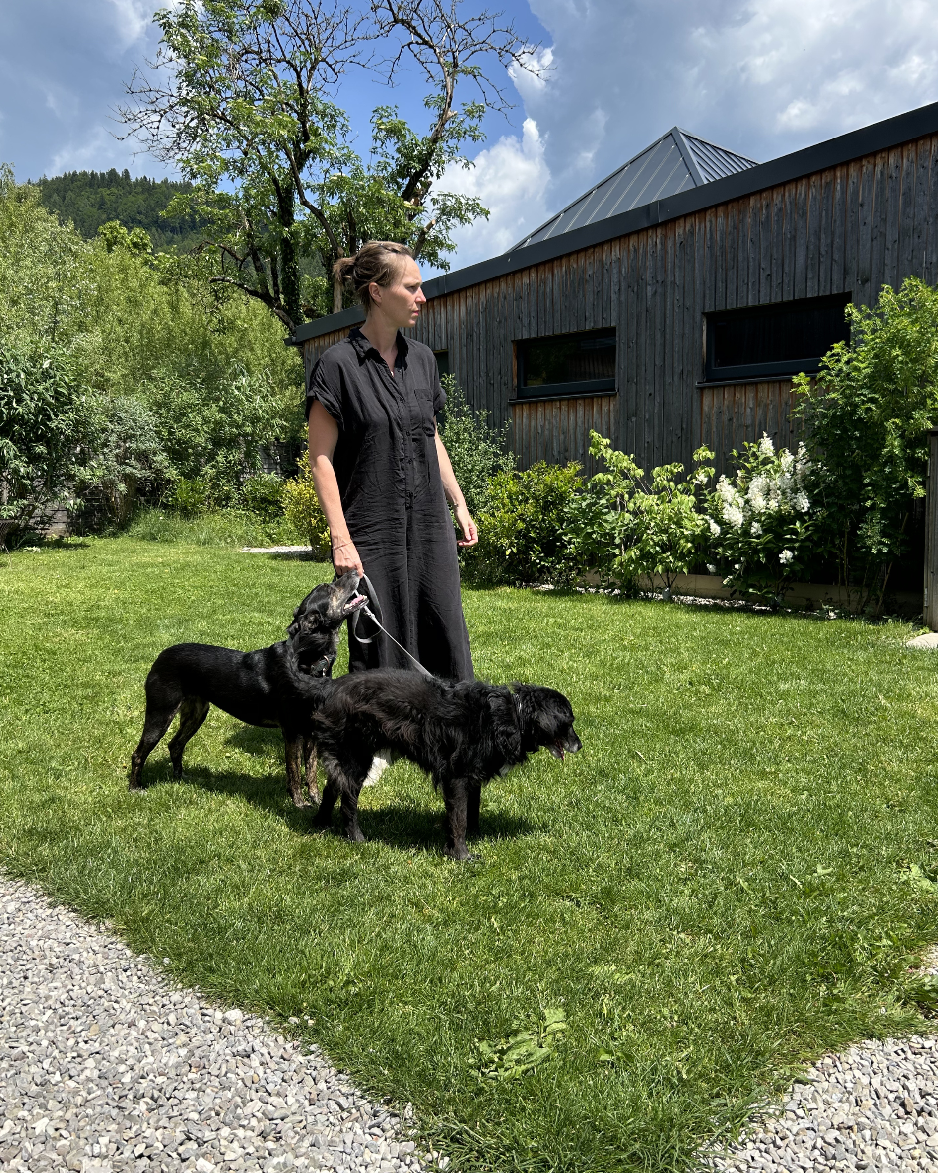 Eine Frau steht mit zwei Hunden auf einer Wiese